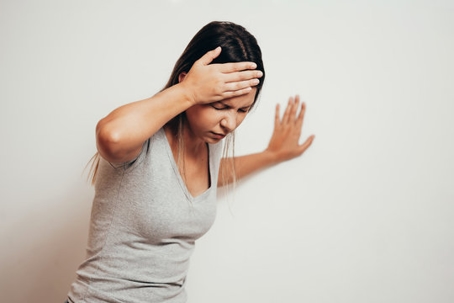 Woman Holding Her Head and Bracing Against a Wall