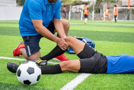 Physical therapist treating soccer injury on the field for an injured player.