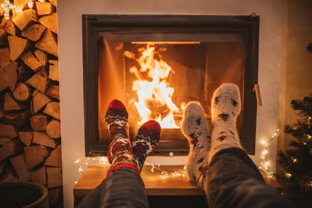 Two people warming their feet by the fire during the holidays. | ProFysio Physical Therapy