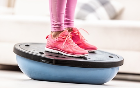Woman doing vestibular therapy exercises on a balance board.