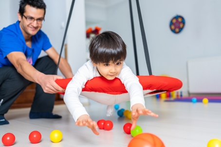 Physical therapist helping a young child with movement activities to assist with motor skills and development. | ProFysio PT