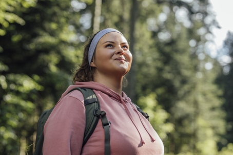Female hiker smiling at the sunlight while taking in the scenery of the trail.