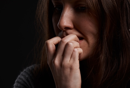 Woman biting her nails, a habit that can strain the jaw and worsen lockjaw symptoms