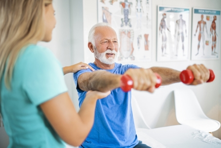Man holding dumbbells during physical therapy session.
