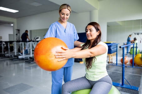 Physical therapist assisting patient with exercise ball workouts as part of her sports rehabilitation plan. | ProFysio Physical Therapy