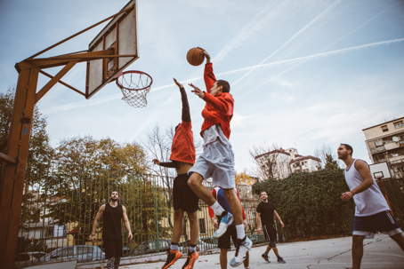 Group of male friends playing basketball at city court