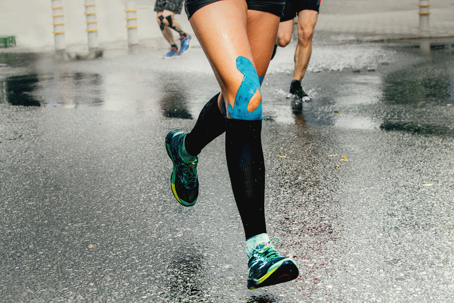 Runner with knee pain using kinesiology tape during outdoor run for patellofemoral pain