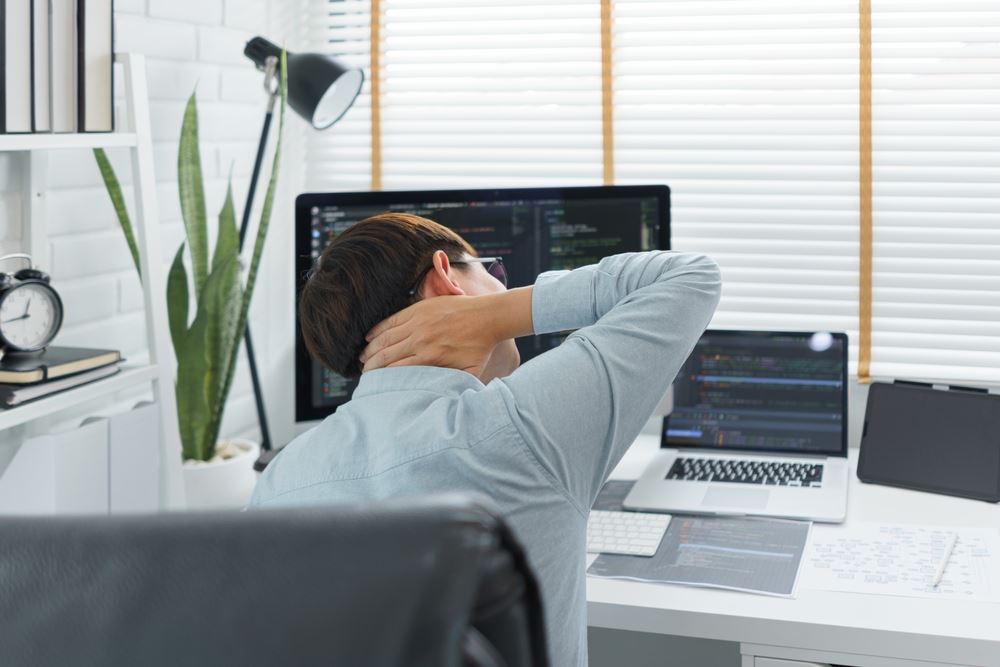 man rubbing his neck at desk